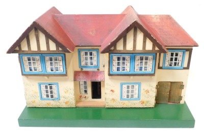 A Tri-ang wooden two storey doll's house, with red painted roof and bay windows, on a green painted rectangular base, 46cm high, 67.5cm wide, 27cm deep.