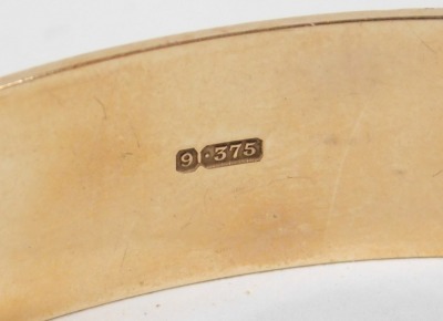 A 9ct gold bangle, with engraved repeating acanthus leaf decoration, on a snap clasp, 24.5g. - 2