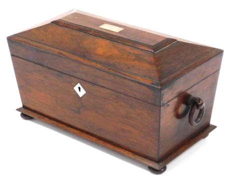 A Regency rosewood tea caddy, of sarcophagus form, with double ring handles, and mother of pearl escutcheons, the hinged lid opening to reveal a fitted interior with central cut glass mixing bowl, flanked by two tea canisters, raised on bun feet, 19cm hig