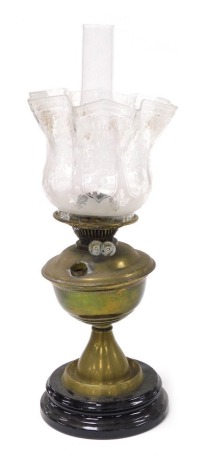 An early 20thC brass oil lamp, raised on a glass socle, with glass chimney and floral etched frilled glass shade, 53cm high.