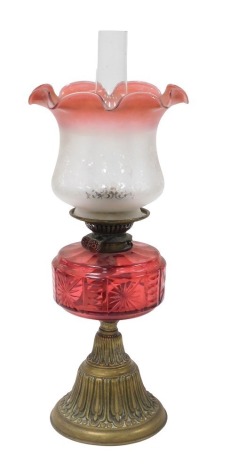 A late 19thC Young's brass oil lamp, with a cranberry glass reservoir, glass chimney and frosted to cranberry etched glass shade, 57cm high.