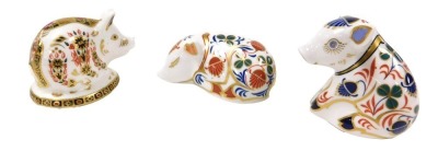 A Royal Crown Derby Imari paperweight, modelled as a sleeping pig, gold stopper, together with two further paperweights, modelled as pigs, silver stoppers. (3)