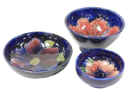 A group of Moorcroft pottery, comprising three bowls decorated in the Hibiscus, Clematis and Anemone patterns, blue ground, printed and painted marks.