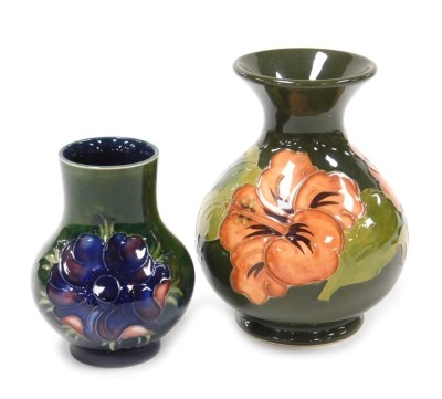 A Moorcroft pottery Anemone pattern vase, of baluster form, green ground, bears paper label, 10cm high, together with a Hibiscus pattern vase, of baluster form, green ground, impressed marks, 13cm high. (2)