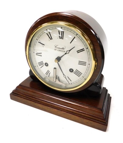 A Comitti of London mahogany cased mantel clock, circular dial bearing Roman numerals, eight day movement with bell strike, the casing of cylindrical form, raised on a pair of smaller cylinders, above a stepped rectangular base, with key, 20cm high.