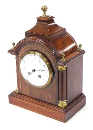 A late 19thC mahogany cased mantel clock, circular enamel dial bearing Arabic numerals, eight day movement by L. Marti et Cie with coil strike, the case of domed and pedimented form, with brass inlay and brass capped reeded quarter columns, raised on a re