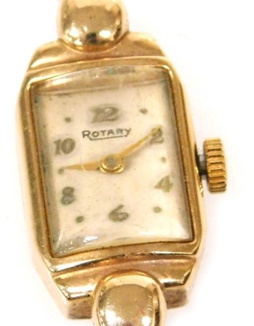 A Rotary lady's 9ct gold cased wristwatch, rectangular cream dial, with Arabic numerals at evens, the case of canted rectangular form, with bulbous lugs, on a 9ct gold bracelet strap, with safety chain, as fitted, 13.4g all in.