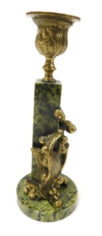 An Art Nouveau green serpentine and brass candlestick, of urn form, raised on a square plinth, with cast brass mistletoe to the front, on a circular base, 16cm high.