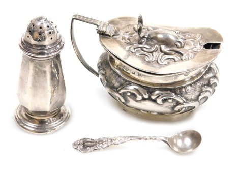 An Edward VII silver mustard pot, with blue glass liner, and embossed foliate scroll decoration, Birmingham 1901, together with a spoon, and a George V silver pepperette, of octagonal form, Birmingham 1927, silver 2.41oz.