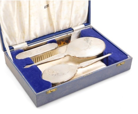 An Elizabeth II four piece silver backed dressing table set, with engine turned and engraved floral decoration, comprising hairbrush, hand mirror, clothes brush and comb, cased, Birmingham 1962.