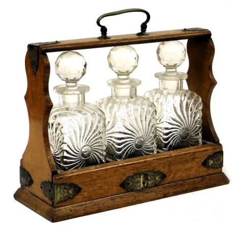 A Victorian oak and silver plated tantalus, with three cut glass decanters and stoppers, no key, 35.cm wide.