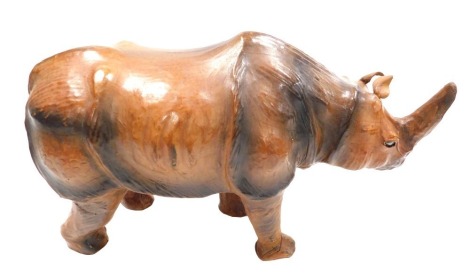 A vintage Liberty style leather bound wooden figure of a rhinoceros, with inset black eyes, 50cm wide.