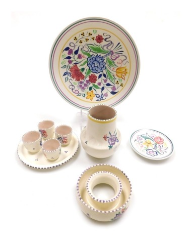 A group of 20thC Poole pottery, traditionally painted with flowers, comprising four egg cups on stand, circular posy holder, vase, dish and a small plate.