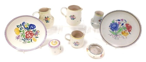 A group of 20thC Poole pottery, traditionally decorated with flowers, comprising three jugs, two plates, circular dish, vase and a preserve pot and cover.