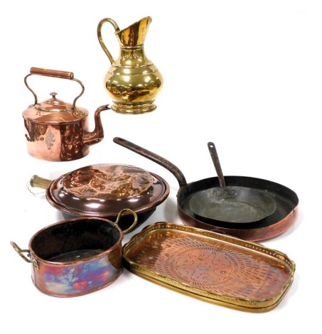 A group of 19thC and later copper ware, including a copper frying pan with cast iron handle, kettle, and an arts and crafts galleried tray, together with a brass jug. (qty)