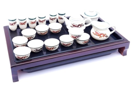 A 20thC Chinese porcelain tea set, decorated with dragons, comprising teapot, jug, bowl and cover, six cups, and ten small bowls, boxed, together with a preparation table.