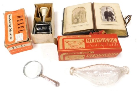 A Rexel numbering machine, A1 hygiene feeding bottle, magnifying glass with silver handle, Sheffield 1918, and a Victorian album of portrait photographs. (4)