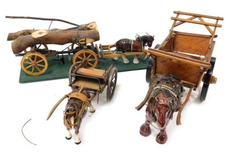 Three pottery cart horses, with wooden carts, one for tree trunk carrying, on a green rectangular base, the small 41cm long and 64cm long.