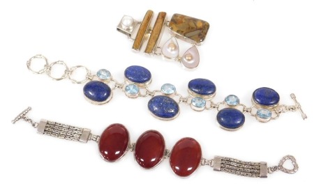 A lapis lazuli and pale blue stone bracelet, in white metal, on a T bar and triple loop, and a further bracelet with three red cabochons, in white metal, with a T and heart shaped clasp, and a blister pearl and agate abstract pendant, in white metal, stam