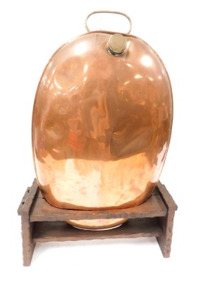 A Georgian copper coach warmer, with a brass handle and water aperture, with screw lid, of oval form, raised on a wooden stand, warmer 61cm wide.