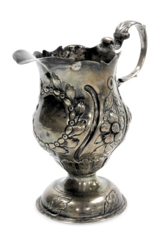 A George III silver cream jug with a later loaded base, of baluster form, embossed with flowers, circular wreath framed reserve, monogram engraved, London 1775, 4.79oz all in. (AF)