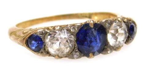 An early 20thC blue and white sapphire five stone ring, set with old cut diamond chippings and the points, in yellow metal, stamped 18ct, size H, 2.6g all in.