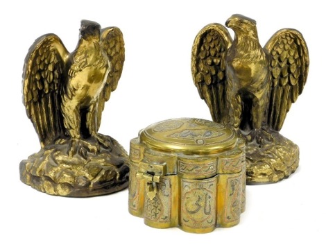 A Damascus brass and inlaid box, of petalled circular form, with fluted sides, decorated in copper and white metal with arabesques, 14cm wide, together with a pair of brass bookends modelled as standing eagles, 21cm high. (3)