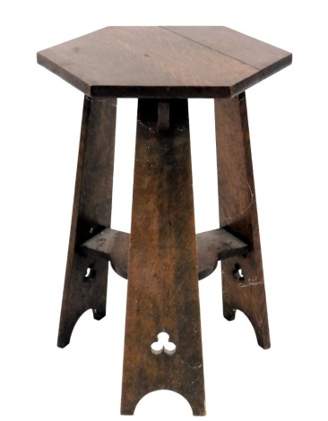 An Arts and Crafts oak occasional table, the hexagonal top on three tapering supports each with pierced decoration, joined by an under tier, 61cm high, 44cm wide.