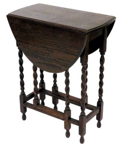 A 1920s oak drop leaf table, with an oval top, on spirally turned supports, 61cm wide.