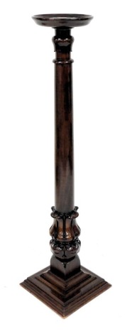 A mahogany torchere or plant stand, with circular dished top, on a turned tapering column carved with leaves, on a square base, 135cm high.