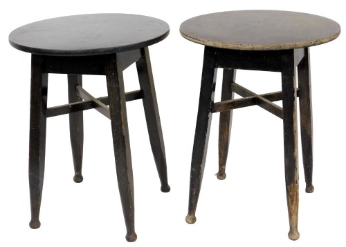 A pair of ebonised oak and laminate pub or cafe tables, in Art and Crafts style, each with a circular top, on square section legs with rounded ends and a X stretcher, 71cm high, 56cm wide.