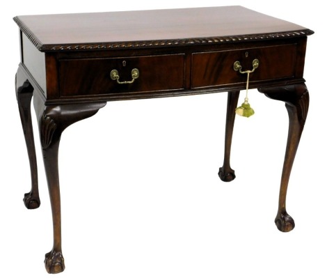 A mid 20thC mahogany serving table, the bow fronted top with a gadrooned edge above two frieze drawers, on shell carved cabriole legs with ball and claw feet, 88cm high, 107cm wide, 62cm deep.