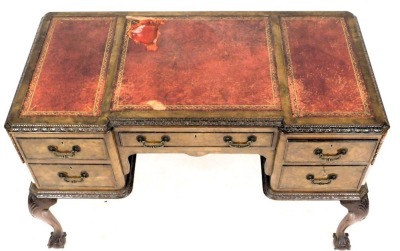 A walnut desk, the break front top with three red and gilt tooled leather insets, surrounded by a leaf carved border above an arrangement of five drawers, each with brass drop handles, on cabriole legs with ball and claw feet, 76cm high, 120cm wide, 61cm - 2