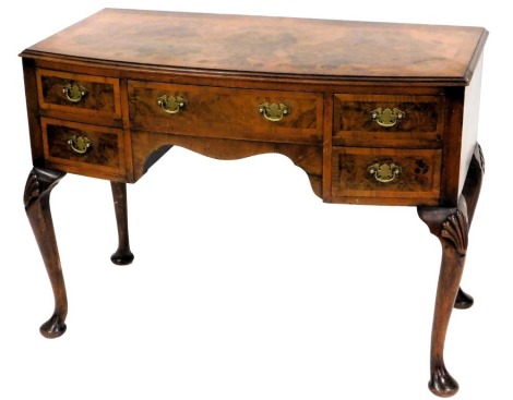 A 1920s cross banded figured walnut bow front dressing table, with frieze drawers and cabriole legs with shell knees and pad feet, 109cm wide.