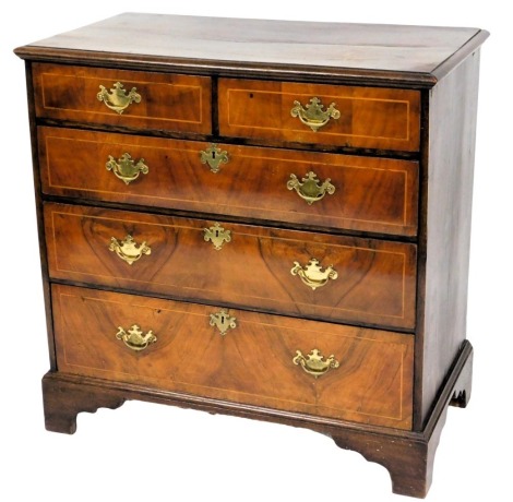 An 18thC oak and walnut chest of drawers, the rectangular top with moulded edge, above two short and three long boxwood strung drawers, each with shaped brass drop handles, on bracket feet, 84cm high, 95cm wide, 52cm deep.
