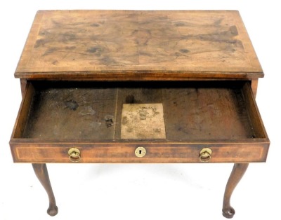 A walnut and feather banded lowboy, the rectangular quarter veneered top with a cross banded border and moulded edge, above arrangement of one long and two short drawers, with brass ring handles, on cabriole legs and pad feet, the drawer bearing label for - 2