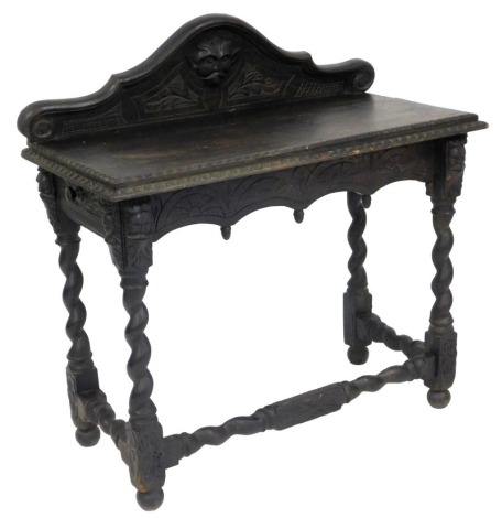 A late Victorian oak side table, the raised back carved with a mask, over a rectangular top with stepped edge, above an arched under tier, on spirally turned supports, 90cm high, 101cm wide, 47cm deep.