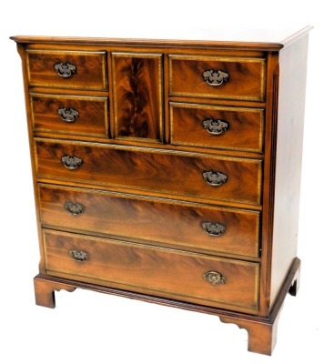 A mahogany and satinwood cross banded television cabinet, formed as a chest of drawers, the rectangular top with a moulded edge, above a top hinged door, formed from a rectangular panel, above four short and two long false drawers, above a real drawer, on