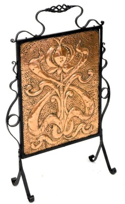 A late 19th/early 20thC wrought iron and embossed copper fire screen, decorated with a tulip and stylised scrolling leaves, 80cm high, 53cm wide.