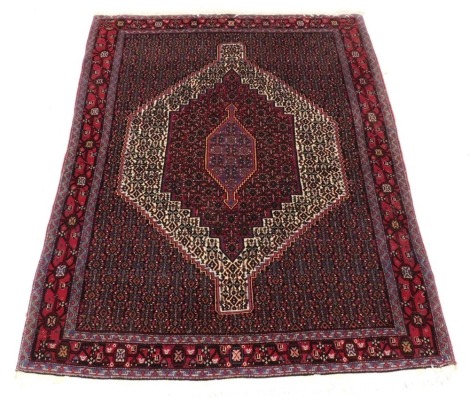 A Persian rug with a central medallion, surrounded by geometric motifs in red, cream pink and blue, one wide, two narrow borders, 159cm x 124cm.