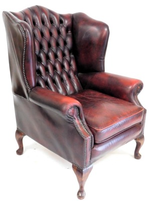 A oxblood red leather upholstered wing back Chesterfield armchair, in George III style with studded borders, on cabriole legs, an a similar stool. The upholstery in this lot does not comply with the 1988 (Fire & Fire Furnishing) Regulations, unless sold - 2