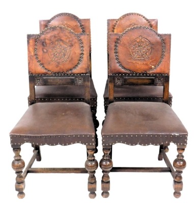 A set of four oak dining chairs, each with a brown leather back, embossed with a rose, within brass beaded borders, with a padded seat, on turned supports with h stretcher.