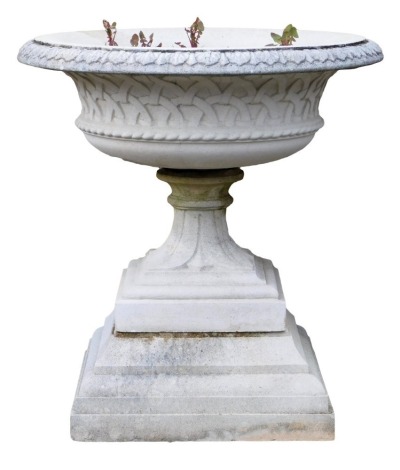 A reconstituted stone garden urn, circular top with a leaf cast border, tapering column, and a square base with stepped plinth, 80cm high, 76cm wide.