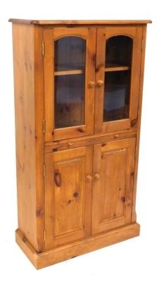 A pine side cabinet, the top with a moulded edge above two glazed doors, a slide and two panelled doors, on a plinth, 143cm high, 77cm wide.