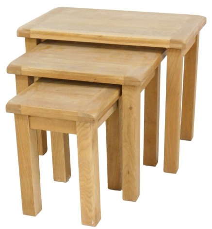 A nest of three light oak tables, of plain form, the largest 68cm wide.