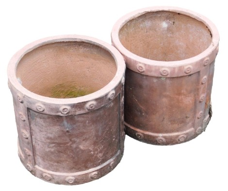 A pair of terracotta coloured cylindrical garden planters, of industrial form with stylised rivets, etc., 30cm high, 31cm diameter.