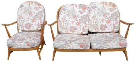 An Ercol elm framed suite, comprising two seater sofa and armchair, model number 203, with removable back and seat cushions, decorated with flowering plants, Asiatic pheasants, etc., in purples, yellows and greens, against an off white ground,...