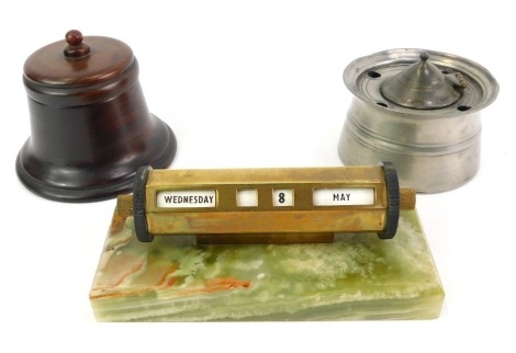 Desk related items, comprising a pewter inkwell, 7cm high, a turned wooden inkwell, 8cm high, and a brass desk calendar, mounted on a green onyx base, 14cm wide.