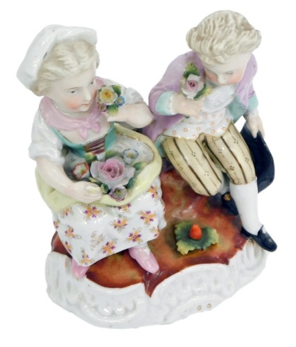 A late 19thC Sitzendorf porcelain figure group, modelled as two seated children with flowers, on an oval rococo scroll base, blue painted mark, 14cm high, 11cm wide.