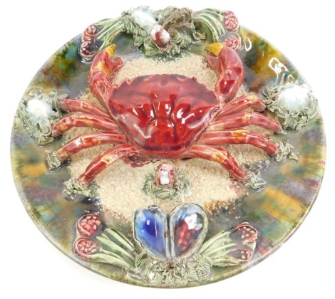 A 20thC Portuguese Caldas da Rainha majolica plate, decorated with a crab amongst shells and seaweed, 23cm diameter.